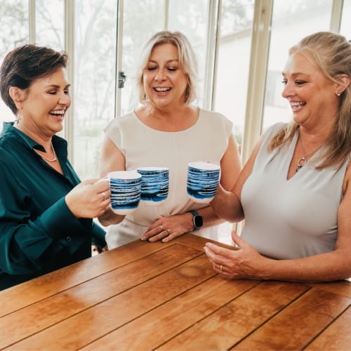 The friendly accounting team behind our reliable BAS Lodgement Sydney services sharing a laugh and clinking coffee mugs together.